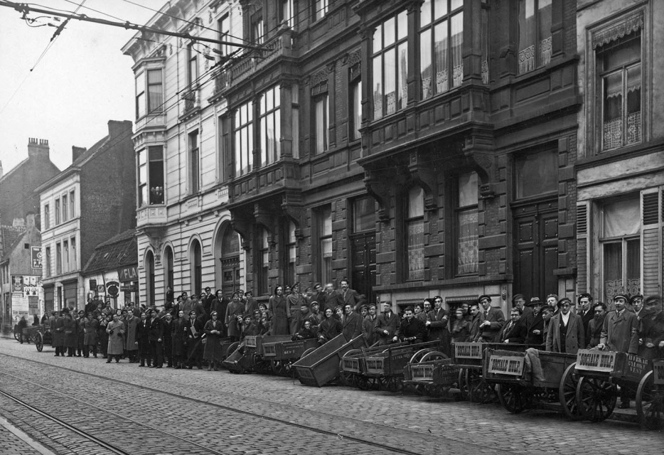Leden van het Gentsch Studentencorps verzamelen in de Sint-Pietersnieuwstraat voor de zogenaamde brigadetochten. Ze komen samen aan studentenhuis Mac Leod om met hun stootkarren de stad in te trekken. Ze bellen aan bij huizen en winkels, en verzamelen voedsel en spullen voor behoeftige Gentenaars in het kader van Sociale Hulp, ca. 1933. (ADVN, VFA2331)