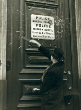 Flor Grammens beschadigt met een hamer een bord met het tweetalige opschrift 'Police bureau central/Politie midden bureel', jaren 1930. (ADVN, VFB665)