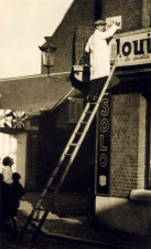 Flor Grammens overschildert een Franstalig straatnaambord, ca. 1937. (ADVN, VFB749)